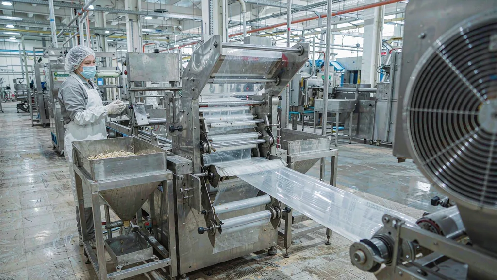 Operator adjusting the forming collar and seal jaws of a form-fill-seal packaging machine during a format changeover in a food factory
