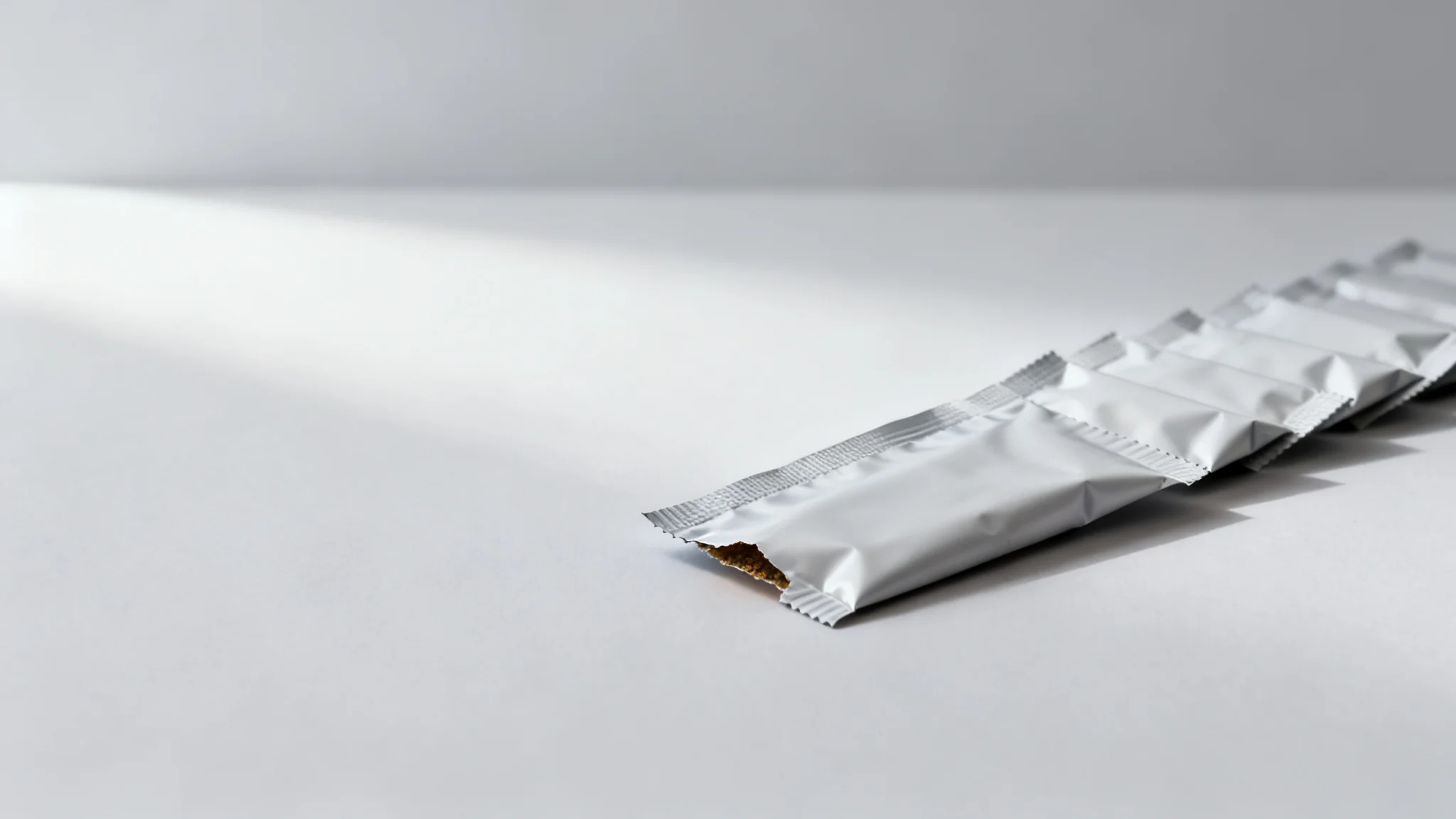 Concept visual of strip-packed unprinted seasoning sachets with a torn end, illustrating seasoning sachet packaging for dosing and tearing